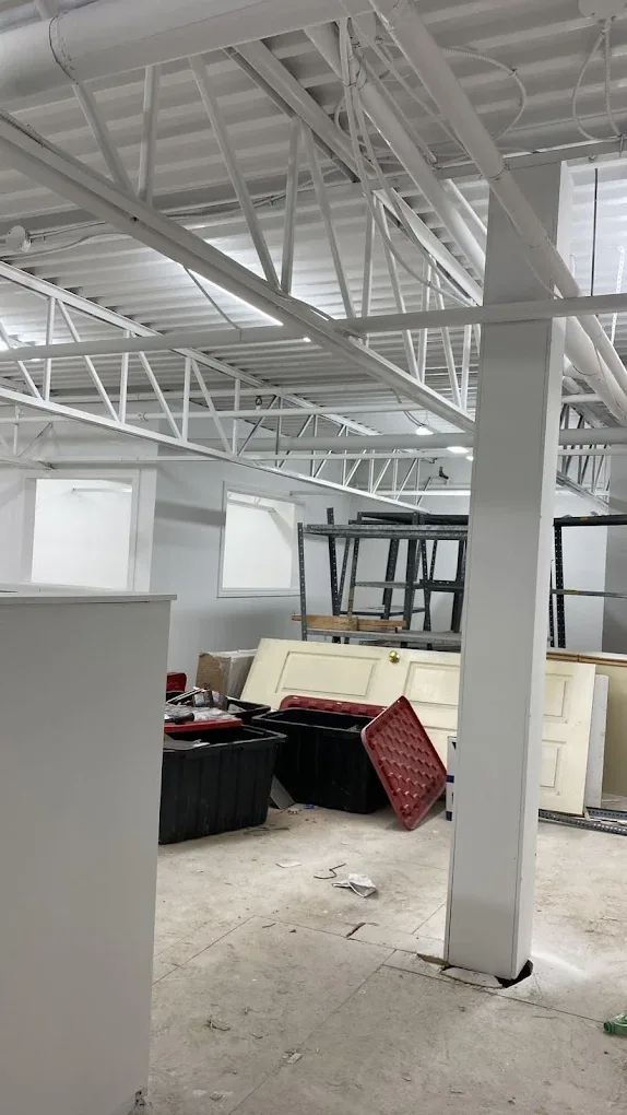 Commercial interior with exposed ceiling structure painted white during preparation