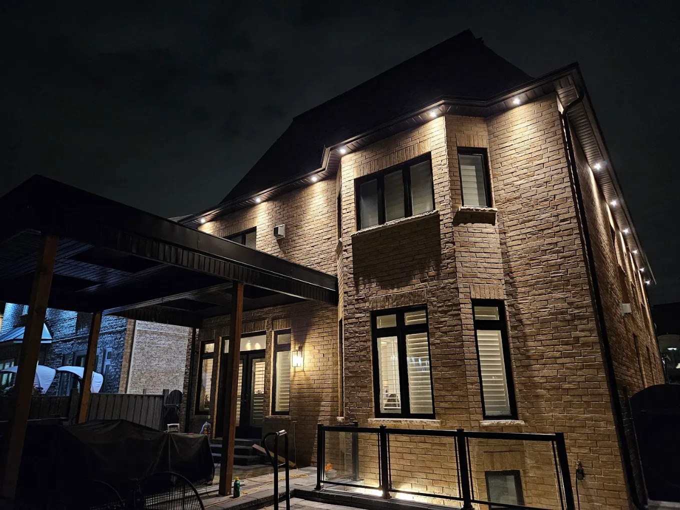 Brick home exterior with dark painted trim illuminated at night