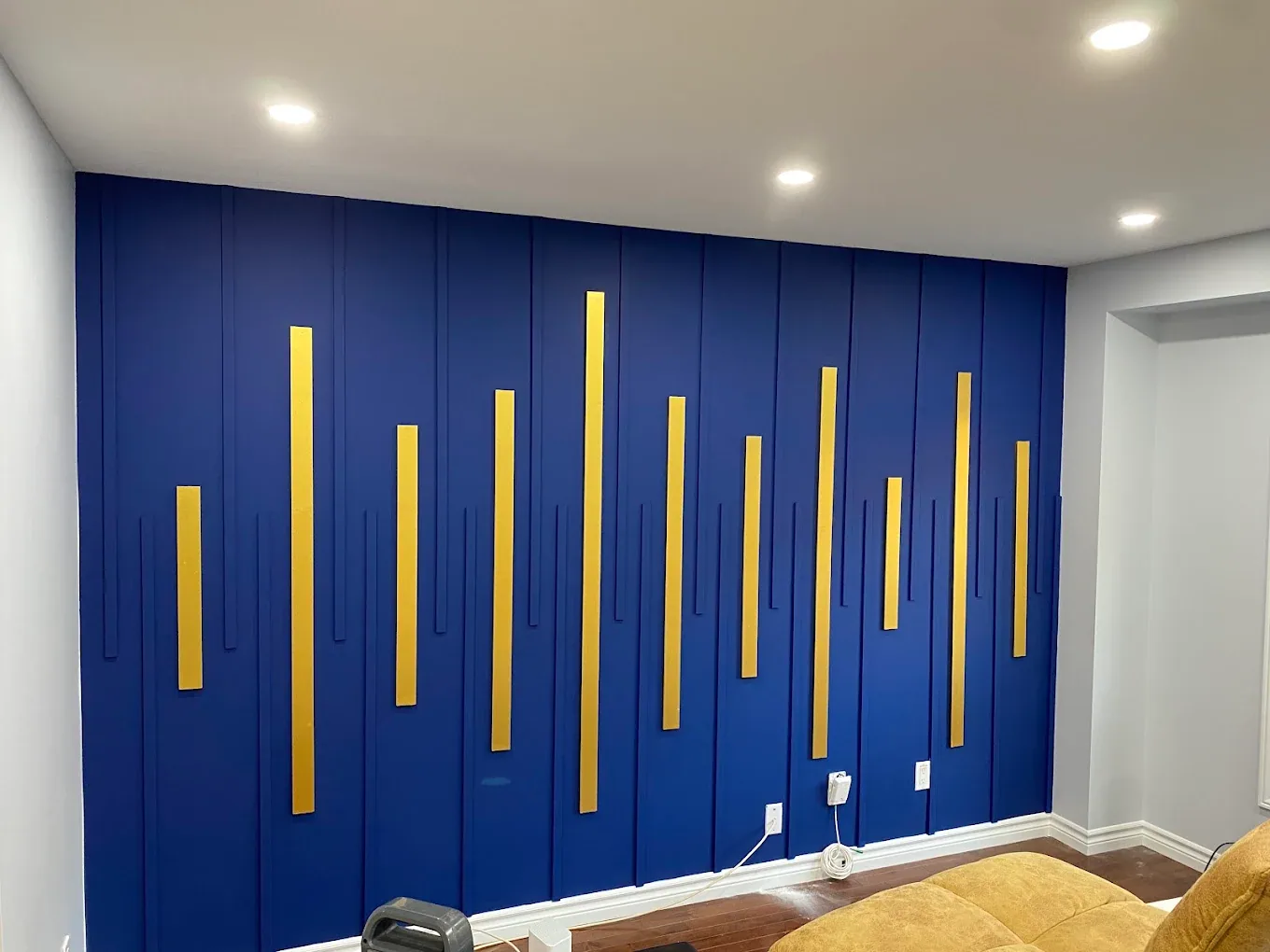 Deep blue feature wall with vertical gold accents in a finished room